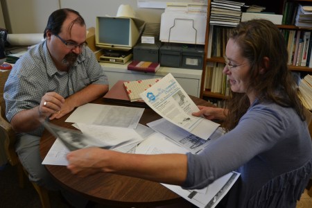 Ron Kelland digs through a stack of papers with Christy in his office