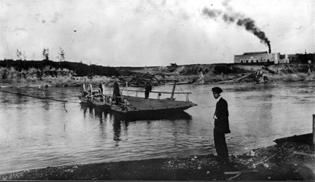 A flat wooden ferry moves towards the shore, and a figure stands on the bank.