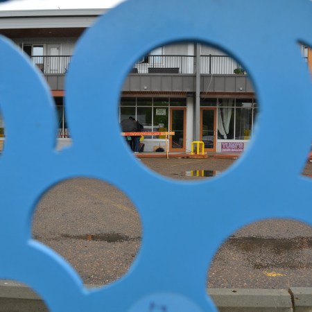 The shop appears as a tiny object through the holes in a bubbly abstract shape in the foreground