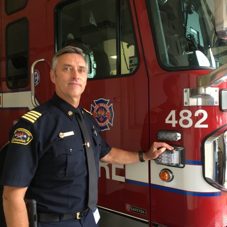 Dave Oldham stands in front of a fire truck.