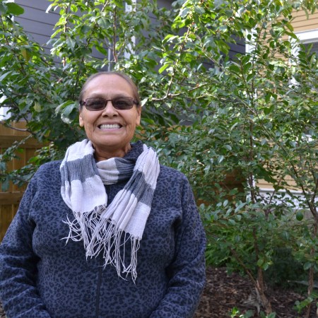 Norma Saddleback standing outside in front of a tree on sunny day in August/ohpahopîsim/ᐅᐦᐸᐦᐅᐲᓯᒼ