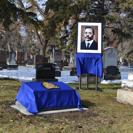 Frank Beevers' touched-up portrait stands in a glass frame on an easel beside his new gravestone, covered by a blue cloth and the Edmonton Police Service logo.