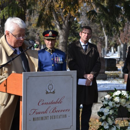 Graham Beevers stands at a podium to say a few words before the unveiling of the gravestone.
