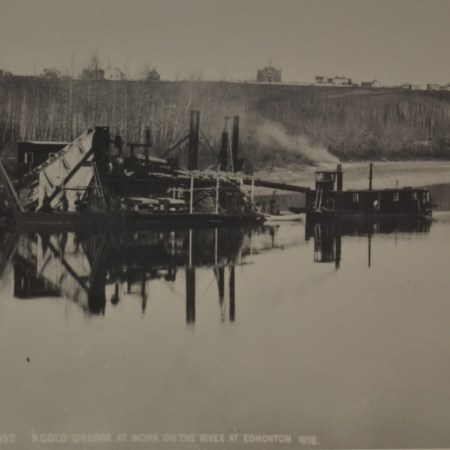 A black and white photo of machinery along a riverbank.