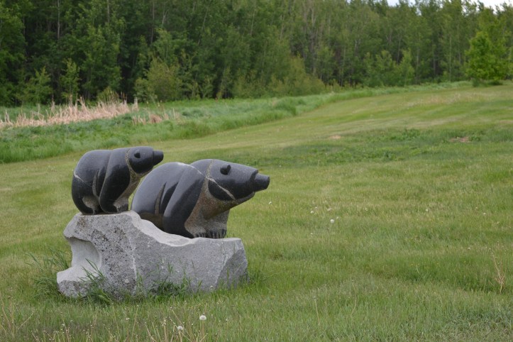 Two bear carvings outside Stewart's studio, with grass behind