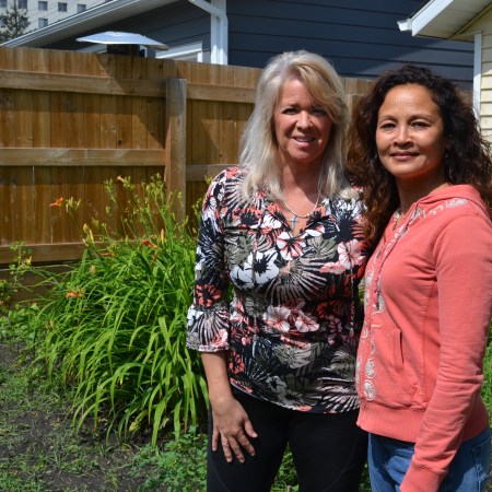 Karen Haugen-Kozyra, President of Viresco Solutions, stands in the garden in front of lilies together with Denise.