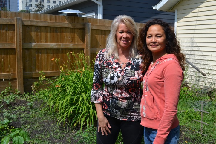 Karen Haugen-Kozyra, President of Viresco Solutions, stands in the garden in front of lilies together with Denise.