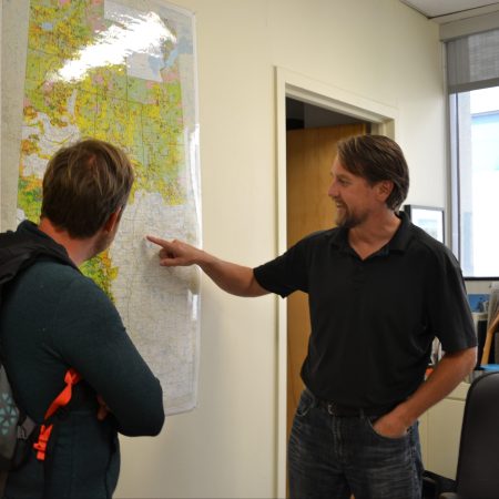 Dustin Bajer and Scott Nielsen look at a map of Alberta in Scotts office
