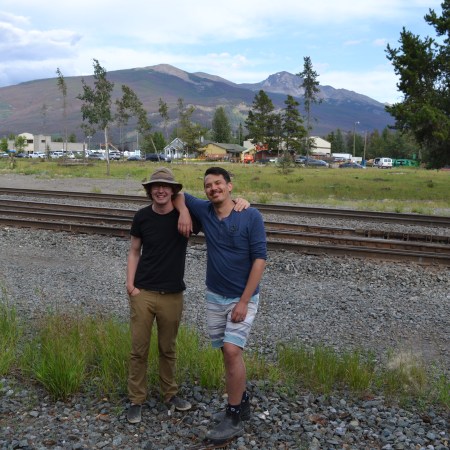 Dylan and Chris smile in front of train tracks in Jasper