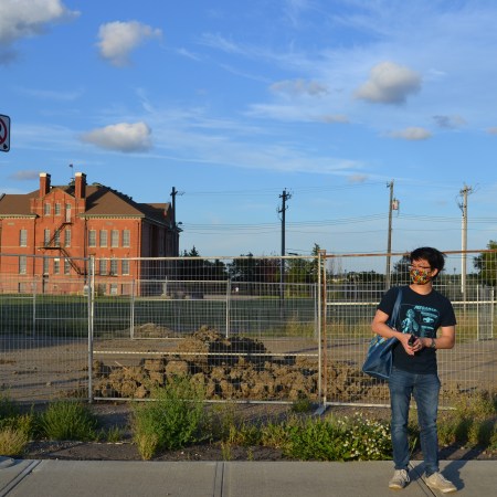A photo of Reporter Nathan Fung in front of the site where the Mirama restaurant once stood, with Alex Taylor School in the background.