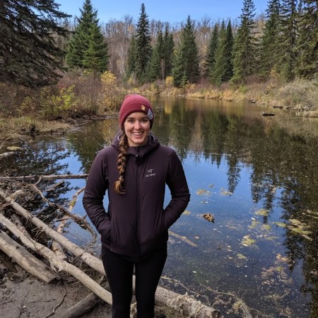 a picture of tara russell standing outside by a pond, smiling