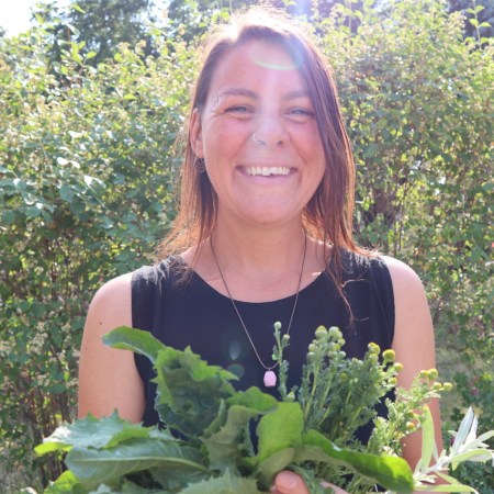 a picture of sarah de lano smiling outside, holding plants