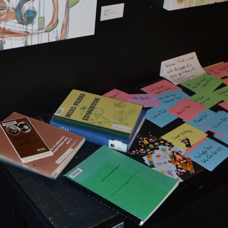 a stack of books about edmonton parks, and a stack of brightly coloured index cards, on a table