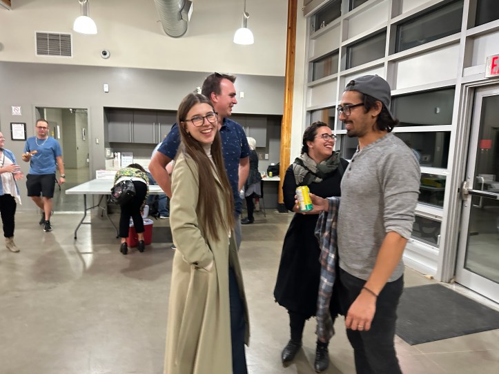 A group of people stand talking and laughing at the Savage Centre.