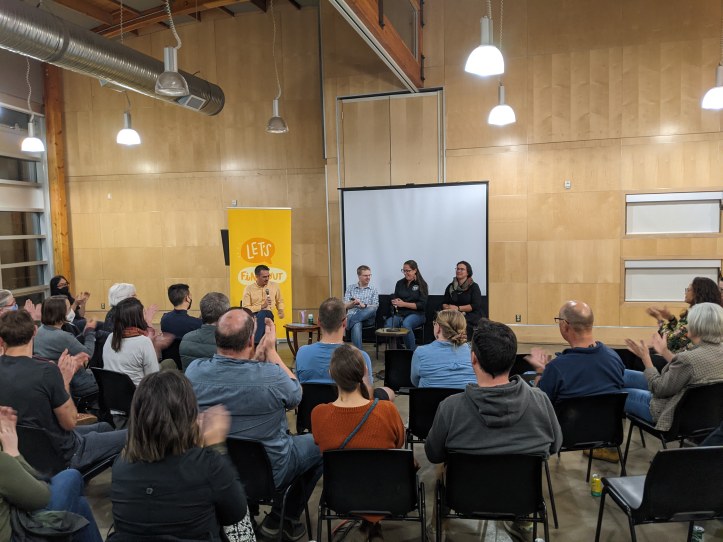 Audience members clap, seated, for speakers Chris Chang-Yen Phillips, Mack Male, Miranda Jimmy, and Lauren Markewicz.