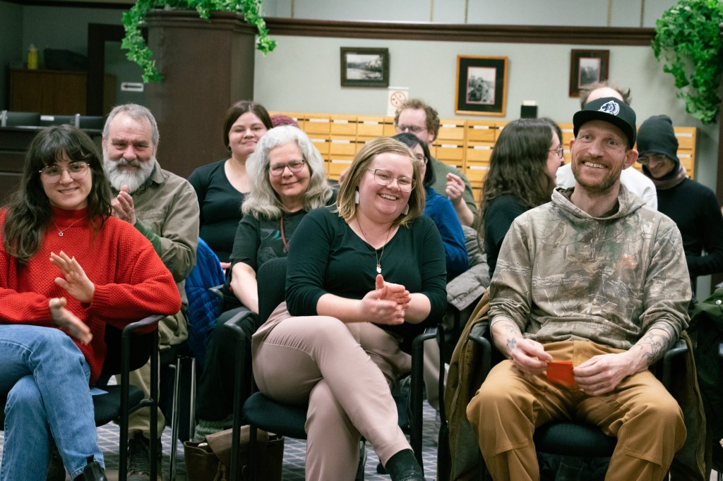 A crowd of people smiling and sitting in chairs
